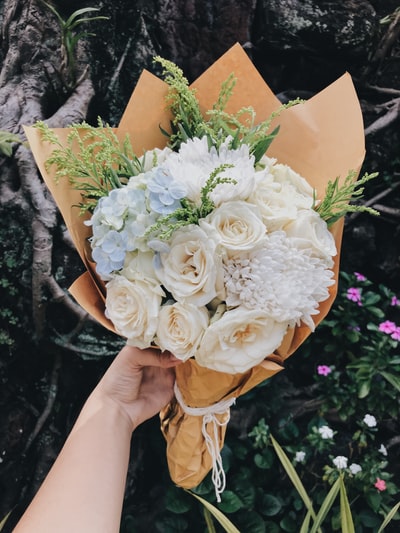 人拿着米色和白色花朵的花束
